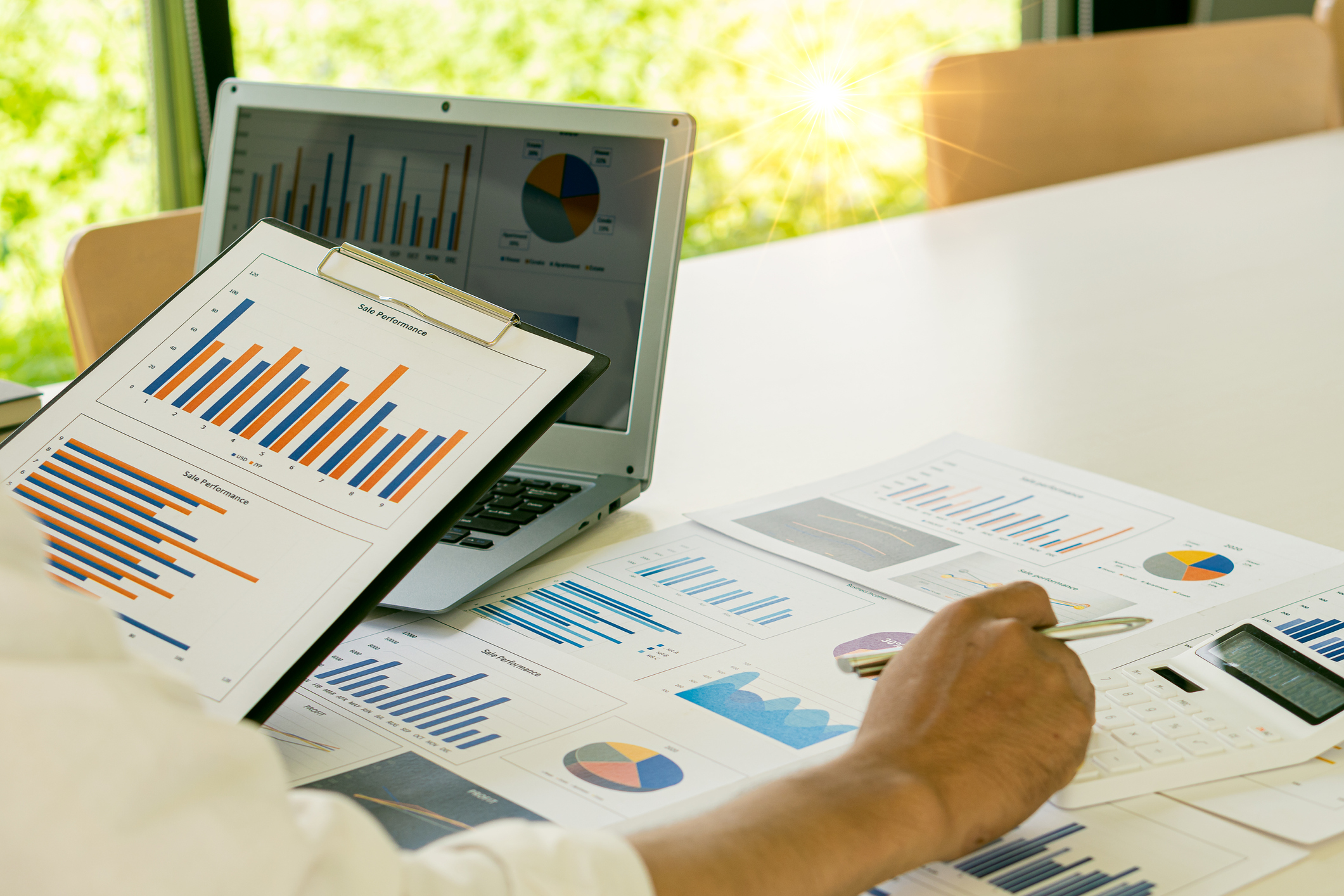 Businessman with pen pointing to graph, financial data, research, develop, market report. Strategic planning, analyzing, calculating financial accounts with calculator and laptop in the office.