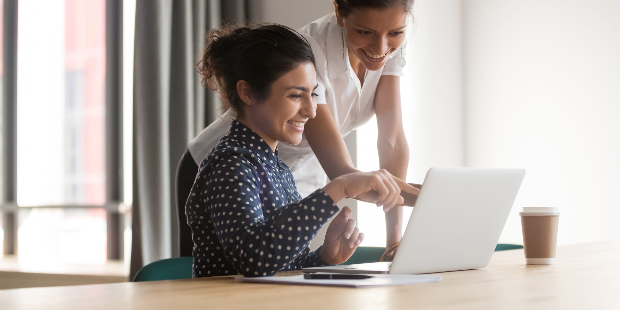 Smiling diverse colleagues talk discussing ideas working on laptop